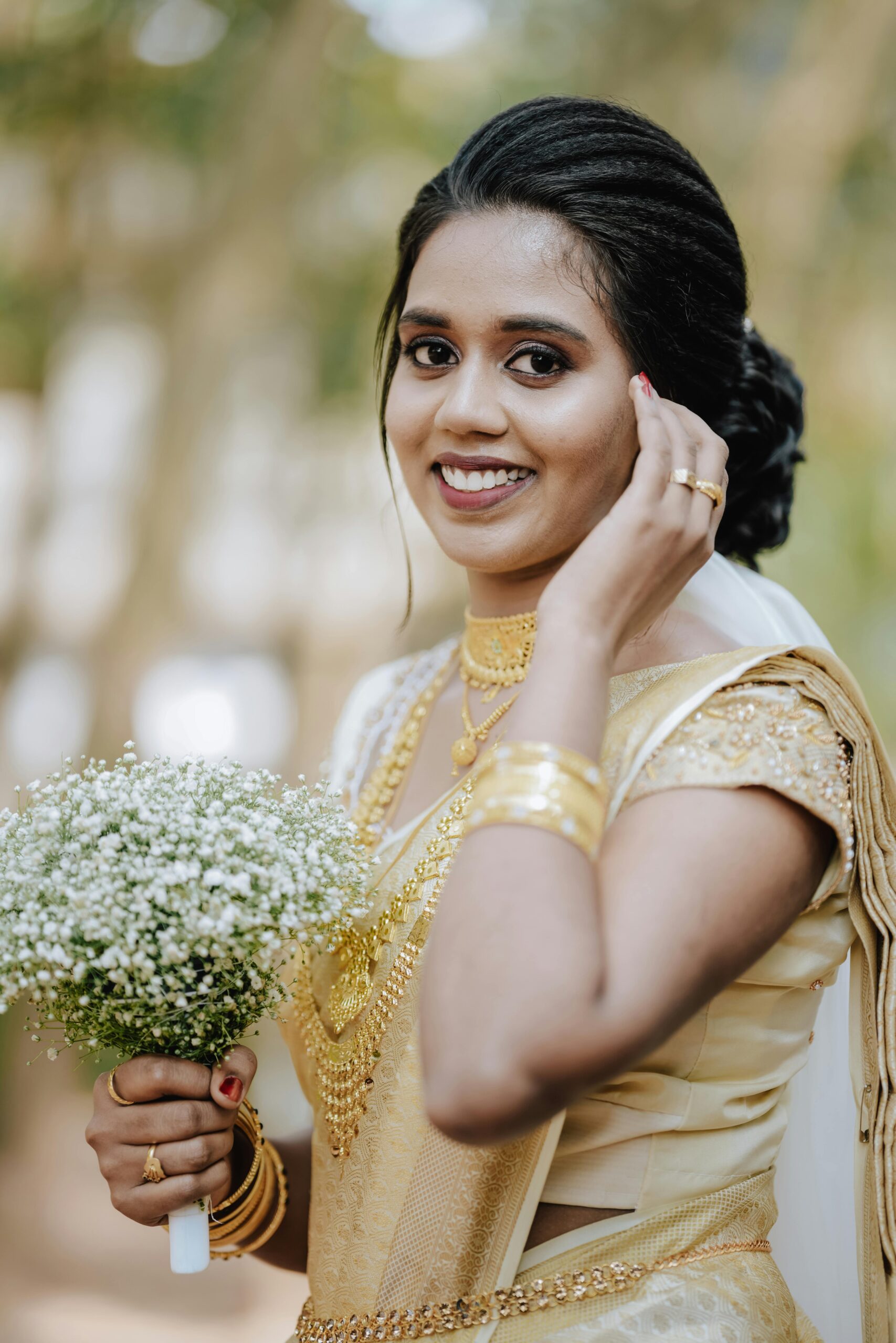 Smiling Indian bride holding a bouquet in traditional golden attire, perfect for wedding themes.