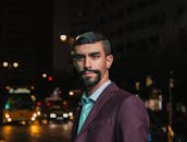 Confident man in a classic suit stands on a vibrant city street at night. Urban nightlife ambiance.